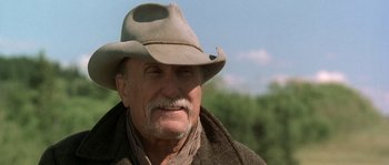 Movie still from “Open Range” (2003), directed by Kevin Costner – An older man wearing a cowboy hat and a scarf; Close Up shot, Low angle