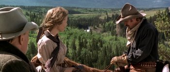 Movie still from “Open Range” (2003), directed by Kevin Costner – A woman in a cowboy hat is holding onto a horse; Medium shot, Over the shoulder angle