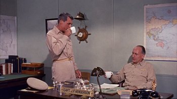 Movie still from “Operation Petticoat” (1959), directed by Blake Edwards – Two men sitting at a table drinking from cups; Medium shot, High angle
