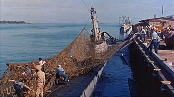 Movie still from “Operation Petticoat” (1959), directed by Blake Edwards – A group of men standing on top of a dock; Wide shot, High angle