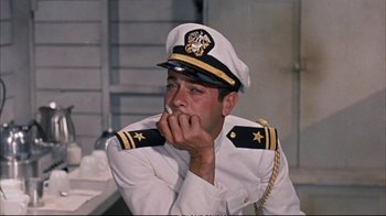 Movie still from “Operation Petticoat” (1959), directed by Blake Edwards – A man in a uniform sitting in front of a table; Medium shot, Low angle