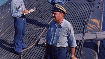 Movie still from “Operation Petticoat” (1959), directed by Blake Edwards – An older man wearing a hat on the deck of a boat; Medium shot, High angle