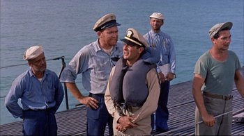 Movie still from “Operation Petticoat” (1959), directed by Blake Edwards – A group of men standing next to each other on a dock; Medium shot, Over the shoulder angle