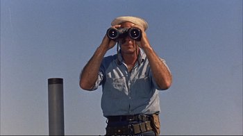Movie still from “Operation Petticoat” (1959), directed by Blake Edwards – A man with a hat on looking through binoculars; Medium shot, Low angle