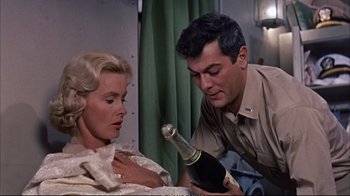 Movie still from “Operation Petticoat” (1959), directed by Blake Edwards – A man and a woman holding a bottle of champagne; Medium shot, High angle
