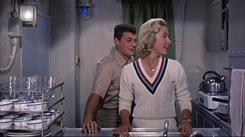 Movie still from “Operation Petticoat” (1959), directed by Blake Edwards – A man and a woman standing next to each other in a room; Medium shot, Over the shoulder angle