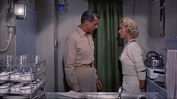 Movie still from “Operation Petticoat” (1959), directed by Blake Edwards – An older man standing next to an older woman in front of a sink; Medium shot, Low angle