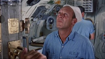 Movie still from “Operation Petticoat” (1959), directed by Blake Edwards – A man in a blue shirt and a white hat is taking a picture of himself; Medium shot, Low angle