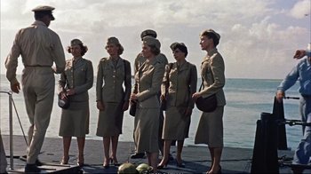Movie still from “Operation Petticoat” (1959), directed by Blake Edwards – A group of women standing next to each other on a dock; Wide shot, Low angle