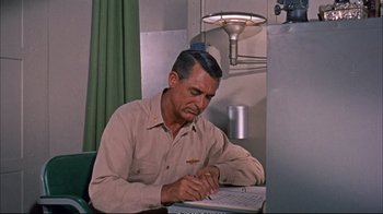 Movie still from “Operation Petticoat” (1959), directed by Blake Edwards – An older man writing on a piece of paper; Medium shot, High angle