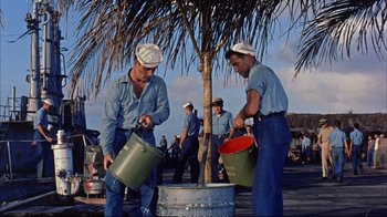 Movie still from “Operation Petticoat” (1959), directed by Blake Edwards – A group of men in blue shirts and white hats are holding buckets; Wide shot, Low angle