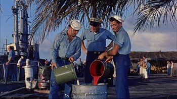 Movie still from “Operation Petticoat” (1959), directed by Blake Edwards – A group of men pouring liquid into a barrel; Wide shot, High angle