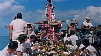 Movie still from “Operation Petticoat” (1959), directed by Blake Edwards – A group of people standing around a pile of food on a boat; Wide shot, High angle