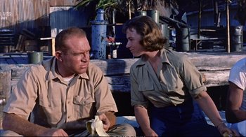Movie still from “Operation Petticoat” (1959), directed by Blake Edwards – A man and a woman sitting next to each other on the ground; Medium shot, Over the shoulder angle