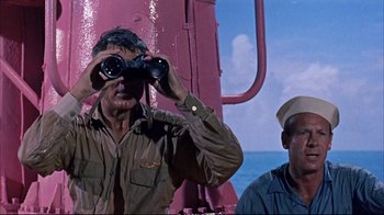 Movie still from “Operation Petticoat” (1959), directed by Blake Edwards – A man looking through binoculars while standing next to another man; Medium shot, Low angle
