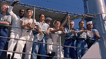 Movie still from “Operation Petticoat” (1959), directed by Blake Edwards – A group of men standing next to each other on a fence; Medium shot, Low angle