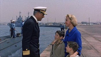 Movie still from “Operation Petticoat” (1959), directed by Blake Edwards – A man in a military uniform standing next to two women and a boy; Medium shot, Over the shoulder angle