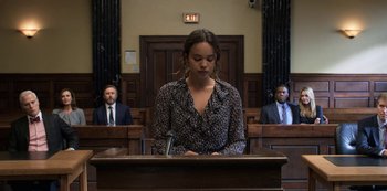 Movie still from “13 Reasons Why” (2017), created by Brian Yorkey – A woman is standing in front of a judge in a courtroom; Medium shot, Low angle