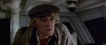 Movie still from “Orca” (1977), directed by Michael Anderson – An older man wearing a hat and a sweater; Close Up shot, High angle
