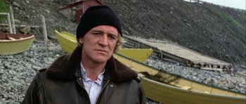 Movie still from “Orca” (1977), directed by Michael Anderson – A man wearing a black hat and a brown jacket; Close Up shot, Low angle