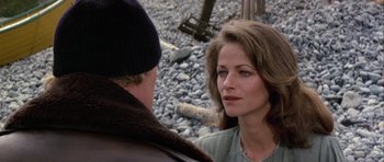 Movie still from “Orca” (1977), directed by Michael Anderson – A woman standing next to a man on some rocks; Close Up shot, Over the shoulder angle