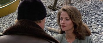 Movie still from “Orca” (1977), directed by Michael Anderson – A woman standing next to a man on a beach; Close Up shot, Over the shoulder angle