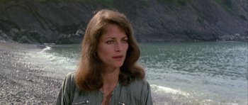 Movie still from “Orca” (1977), directed by Michael Anderson – A woman standing in front of a body of water; Close Up shot, Low angle