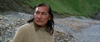 Movie still from “Orca” (1977), directed by Michael Anderson – A man with long black hair wearing a beige sweater; Close Up shot, Low angle