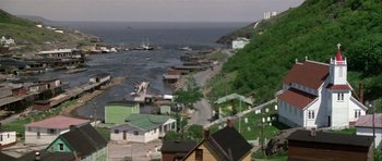 Movie still from “Orca” (1977), directed by Michael Anderson – An aerial view of a small town with a body of water in the background; Extreme Wide shot, High angle