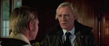 Movie still from “Orca” (1977), directed by Michael Anderson – A man in a suit and tie talking to another man in a suit and tie; Close Up shot, Over the shoulder angle