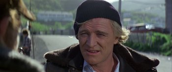 Movie still from “Orca” (1977), directed by Michael Anderson – A person wearing a jacket and a hat; Close Up shot, Low angle