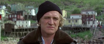 Movie still from “Orca” (1977), directed by Michael Anderson – A person wearing a jacket and a hat; Close Up shot, Low angle