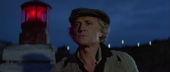 Movie still from “Orca” (1977), directed by Michael Anderson – A man in a hat and sweater looking at the camera; Close Up shot, Low angle
