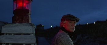 Movie still from “Orca” (1977), directed by Michael Anderson – An older man wearing a sweater and a cap; Medium shot, Low angle