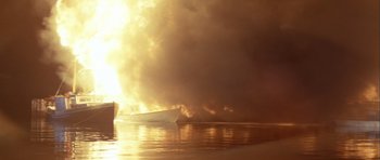 Movie still from “Orca” (1977), directed by Michael Anderson – A boat on fire in the middle of a body of water; Extreme Wide shot, Low angle