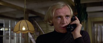 Movie still from “Orca” (1977), directed by Michael Anderson – A man talking on a phone while wearing a black shirt; Close Up shot, Low angle
