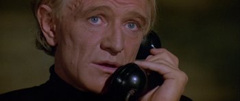Movie still from “Orca” (1977), directed by Michael Anderson – A man talking on a phone while wearing a black shirt; Close Up shot, Low angle