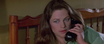 Movie still from “Orca” (1977), directed by Michael Anderson – A woman is talking on a phone while sitting in a chair; Close Up shot, High angle