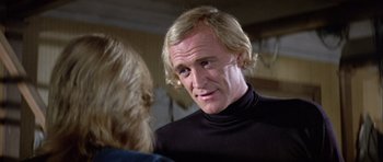 Movie still from “Orca” (1977), directed by Michael Anderson – A person talking to another person; Close Up shot, Over the shoulder angle