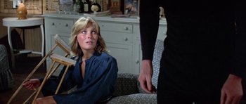 Movie still from “Orca” (1977), directed by Michael Anderson – A woman sitting on a couch next to a man in a room; Medium shot, Over the shoulder angle