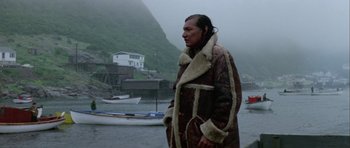 Movie still from “Orca” (1977), directed by Michael Anderson – A man standing in front of a body of water; Medium shot, Low angle