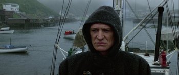 Movie still from “Orca” (1977), directed by Michael Anderson – A man wearing a hooded jacket on a boat; Close Up shot, Low angle