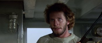 Movie still from “Orca” (1977), directed by Michael Anderson – A person wearing a sweater and looking at the camera; Close Up shot, Low angle