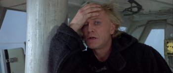 Movie still from “Orca” (1977), directed by Michael Anderson – A person holding his hand to his forehead; Close Up shot, Low angle