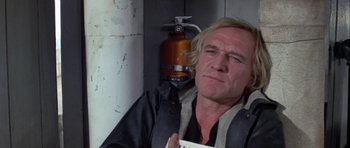 Movie still from “Orca” (1977), directed by Michael Anderson – A person holding a paper near a fire hydrant; Close Up shot, Low angle