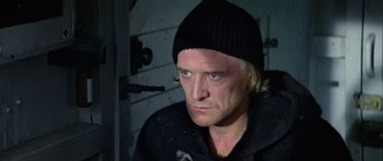 Movie still from “Orca” (1977), directed by Michael Anderson – A person wearing a black hat; Close Up shot, Over the shoulder angle