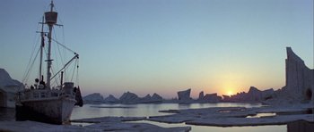 Movie still from “Orca” (1977), directed by Michael Anderson – The sun is setting over a body of water; Extreme Wide shot, Low angle