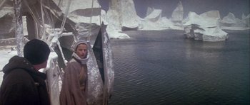 Movie still from “Orca” (1977), directed by Michael Anderson – A woman standing in front of a body of water; Wide shot, High angle