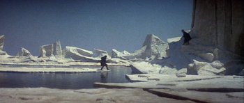 Movie still from “Orca” (1977), directed by Michael Anderson – A person standing in the middle of a body of water; Extreme Wide shot, High angle