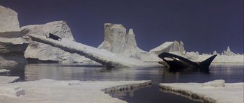 Movie still from “Orca” (1977), directed by Michael Anderson – A person holding an umbrella while standing in the water; Extreme Wide shot, High angle
